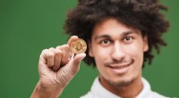 homem segurando uma moeda física de bitcoin