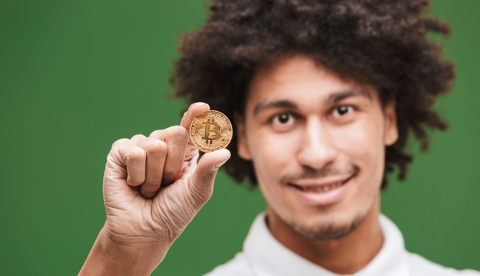 homem segurando uma moeda física de bitcoin