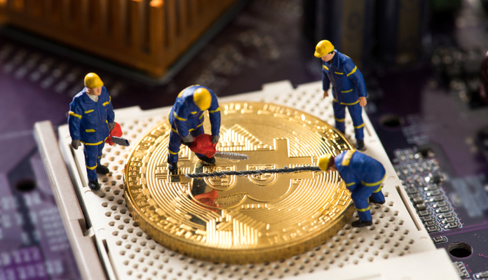 Miniaturas de homens em cima de moeda de Bitcoin gigante fazendo medição pela metade