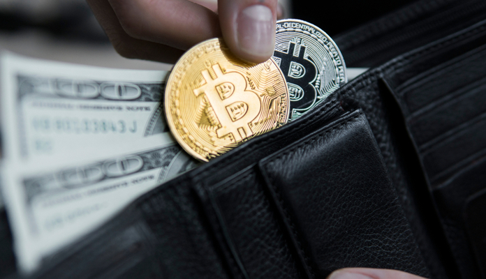 Carteira com duas moedas de bitcoin e notas de dólar