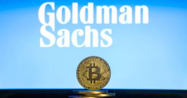 moeda de Bitcoin à frente do logotipo do Goldman Sachs