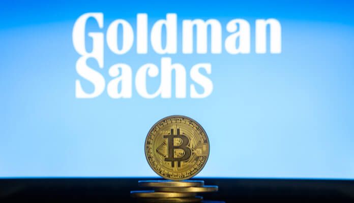 moeda de Bitcoin à frente do logotipo do Goldman Sachs