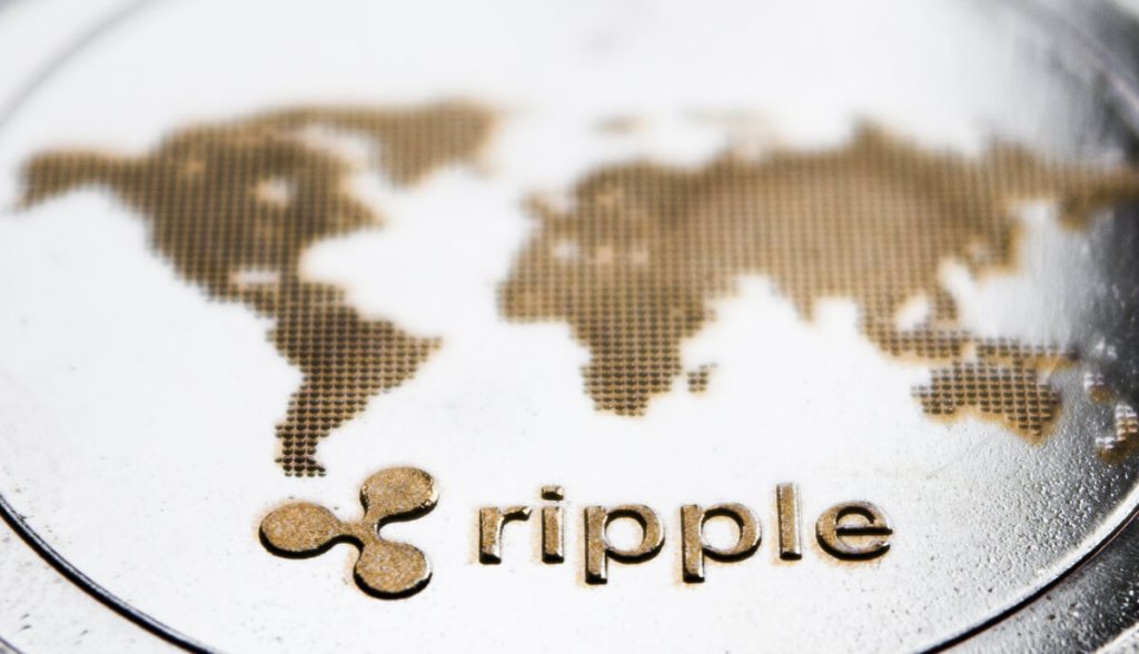 Moeda prateada com logo da ripple em meio a mapa mundi
