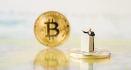 miniatura de homem sob pulpito e moeda gigante de bitcoin ao lado