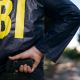 Agente do FBI retirando arma das costas