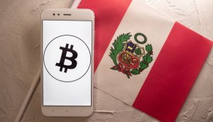 Celular com logo do Bitcoin à frente de bandeira do Peu