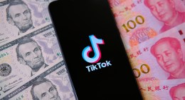 celular com logo do TikTok em cima de notas de dólares