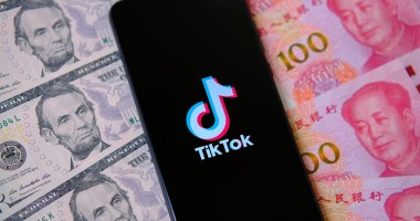 celular com logo do TikTok em cima de notas de dólares