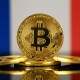 Moedas de Bitcoin diante de bandeira da França