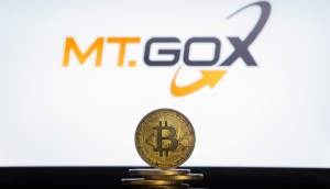 Moeda de Bitcoin à frente de logo da Mt. Gox