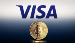 Logotipo da Visa acima de moeda de Bitcoin
