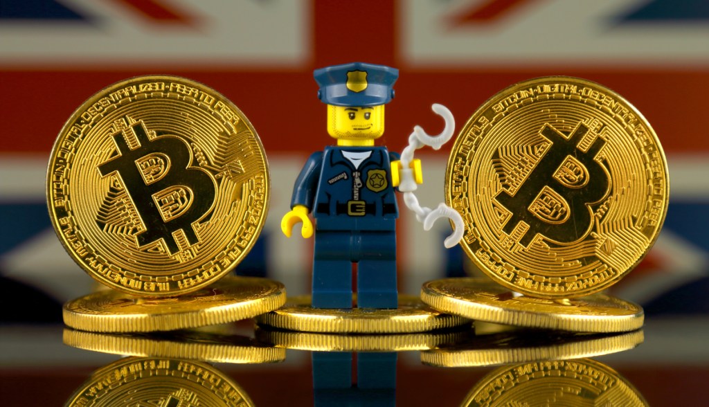 miniatura de soldado em em meio a moedas de Bitcoin-ao fundo, bandeira da Inglaterra