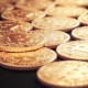 Moedas Douradas de Bitcoin em cima de uma superfície preta