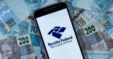 Celular com logotipo da Receita Federal sobre notas de reais