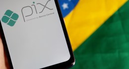 Celular com logo do Pix sob bandeira do Brasil