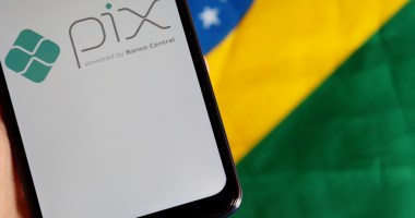 Celular com logo do Pix sob bandeira do Brasil