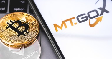 Moeda de bitcoin ao lado de smartphone com logotipo da corretora Mt.Gox
