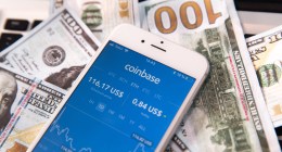 celular com logo da Coinbase em cima de notas de dinheiro