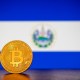 Moeda de Bitcoin à frente de bandeira de El Salvador