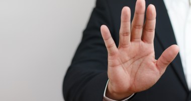 Uma pessoa acena com uma das mãos em sinal de pare