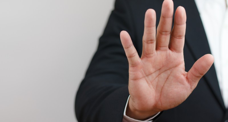 Uma pessoa acena com uma das mãos em sinal de pare