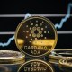 Moeda dourada com logo da Cardano na rente de gráfico com alta