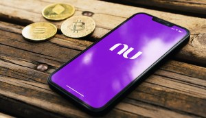 Sob um banco de madeira três criptomoedas ao lado de um celular com logo do Nubank