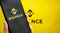 Celular com logo da Binance na frente de um fundo amarelo com logo da Binance.jpg