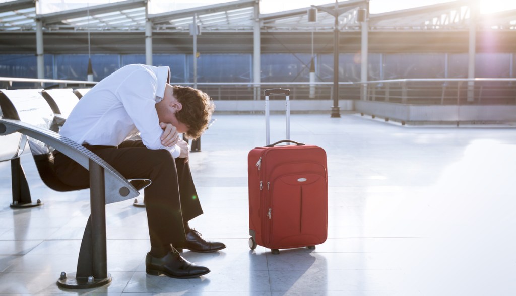 Homem triste sentado em um banco de aeroporto