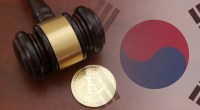 Martelo de juiz e moeda física de bitcoin sob uma base com a abndeira da Coreia do Sul