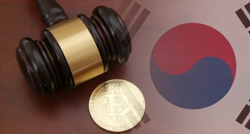 Martelo de juiz e moeda física de bitcoin sob uma base com a abndeira da Coreia do Sul