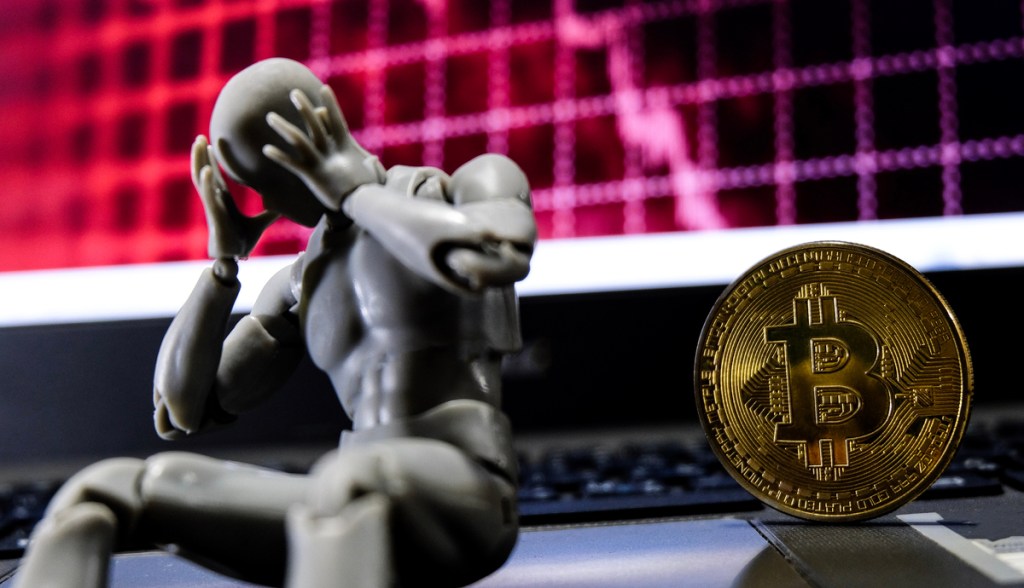 um robô triste sentado na frente do bitcoin em crise