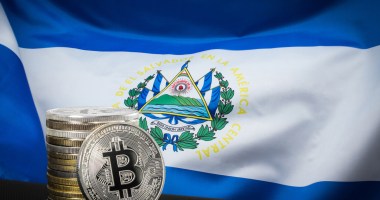 Bandeira de El Salvador ao fundo, e moedas de Bitcoin