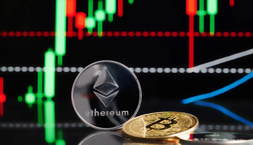 Moedas de Ethereum e Bitcoin em frente a um gráfico de candles em uma tela
