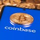 moeda bitcoin em cima de celular com logo da coinbase