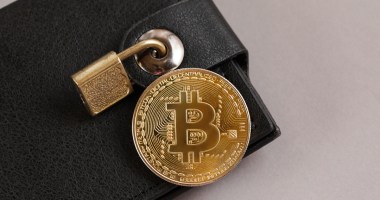 moeda de bitcoin em cima de uam carteira de bolso fechada com um cadeado