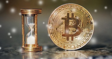 Ampulheta com tempo acabando ao lado de uma moeda de bitcoin