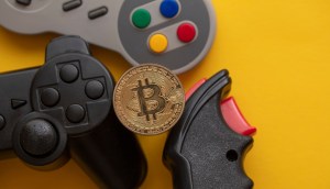 Controles de videogames e uma moeda dourada de Bitcoin (BTC)