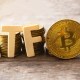 Letras que formam a sigla ETF próximas a uma moeda dourada de Bitcoin (BTC)