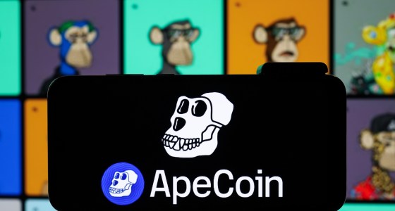 Símbolo da ApeCoin (APE) na tela de um celular e NFTs da coleção Bored Ape Yacht Club (BAYC) desfocados atrás