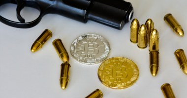 Uma pistola, munições e moeda de bitcoin sobre uma mesa