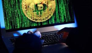 Tela de computador que mostra moeda de bitcoin em meio a traços matrix