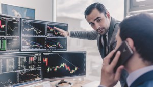 Investidores olham telas com graficos de mercado