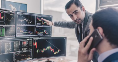 Investidores olham telas com graficos de mercado