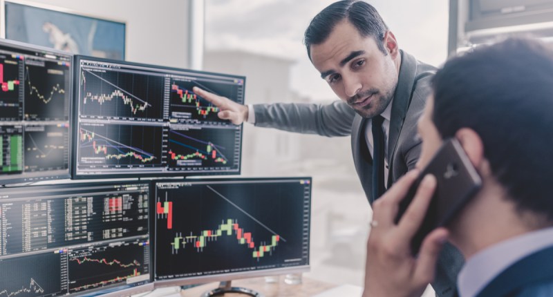 Investidores olham telas com graficos de mercado