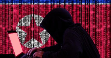 Hacker mexendo em notebook com bandeira da Coreia do Norte no fundo