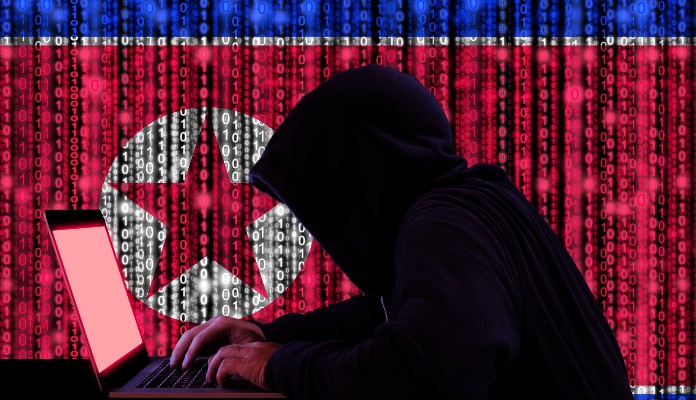 Hacker mexendo em notebook com bandeira da Coreia do Norte no fundo