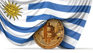 Moeda de bitcoin semicoberta por bandeira nacional do Uruguai