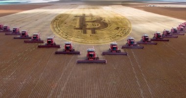 Símbolo do bitcoin em meio a máquinas agrícolas e plantação