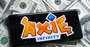 Smartphone sobre dólares mostra logo Axie Infinity
